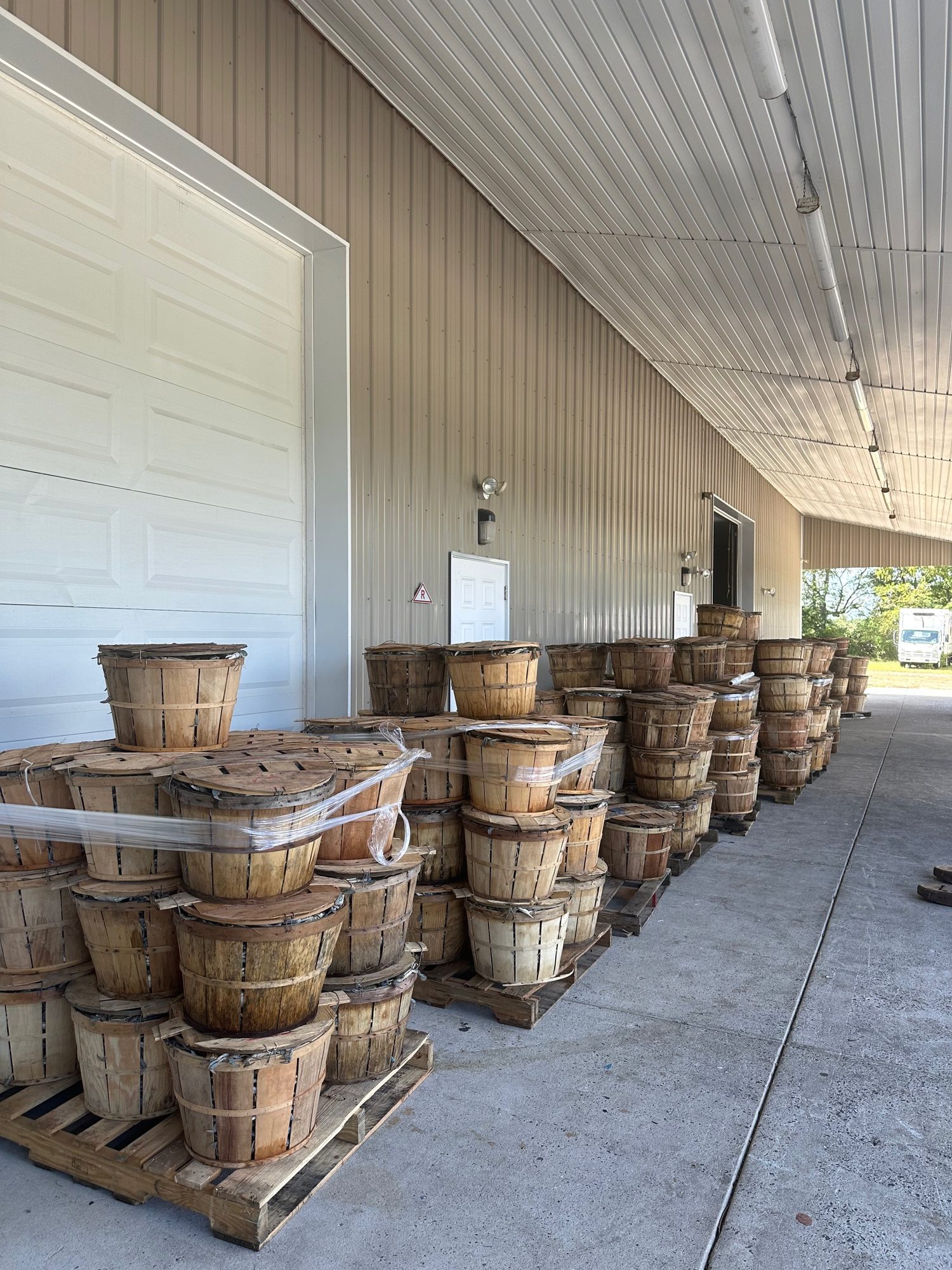 Pallets of wooden bushel baskets along the house